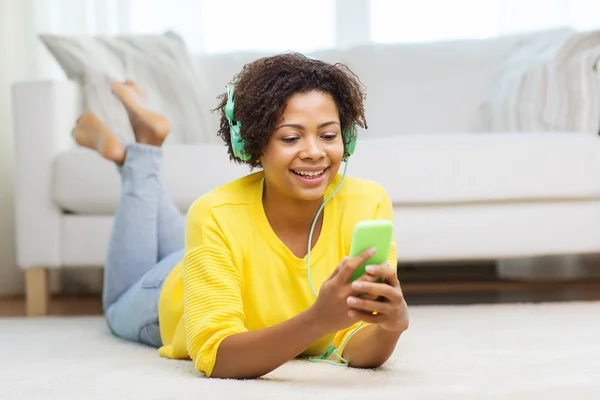 Mujer africana feliz con teléfono inteligente y auriculares —  Fotos de Stock