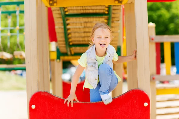 Fröhliches kleines Mädchen klettert auf Kinderspielplatz — Stockfoto