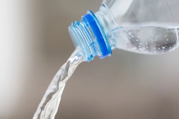 Primo piano dell'acqua versata dalla bottiglia di plastica — Foto Stock