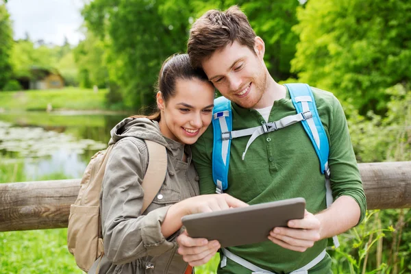 Gelukkige paar met rugzakken en tablet pc buitenshuis — Stockfoto