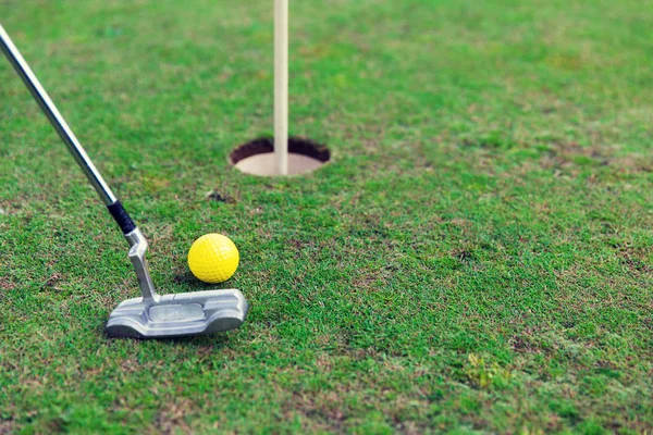Клуб и мяч возле лунки на поле для гольфа — стоковое фото