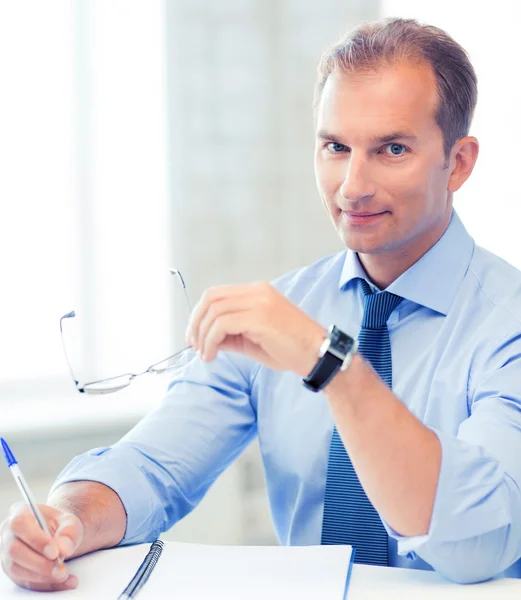 Geschäftsmann mit Brille schreibt in Notizbuch — Stockfoto