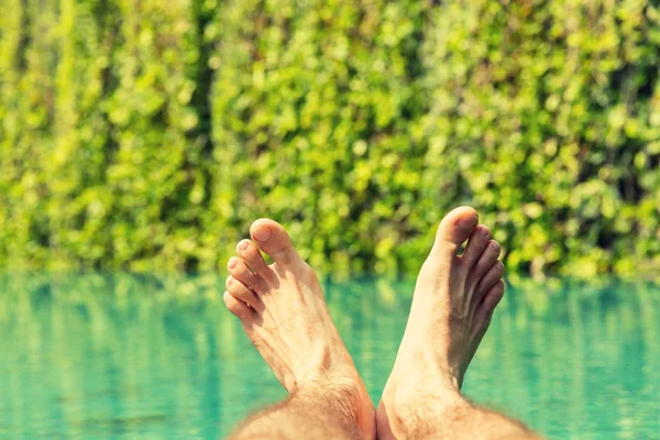 Manliga fötter över Resort pool — Stockfoto