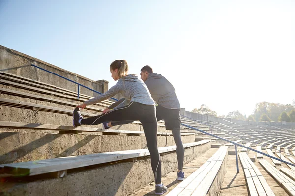 Paar stretching been op stands van stadion — Stockfoto