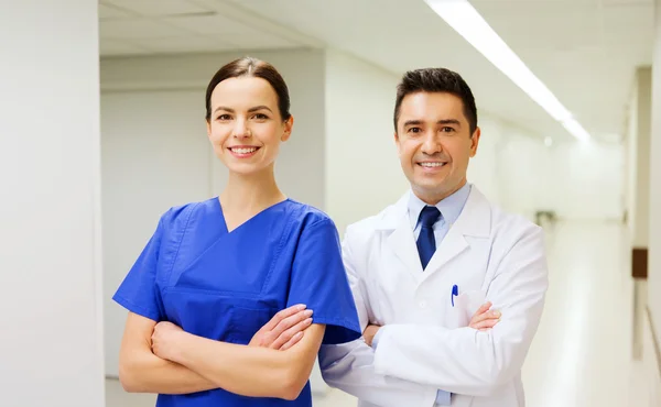 Smiling doctor in white coat and nurse at hospital — Stock Photo, Image