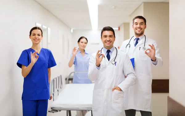 Médicos felizes com maca mostrando ok no hospital — Fotografia de Stock
