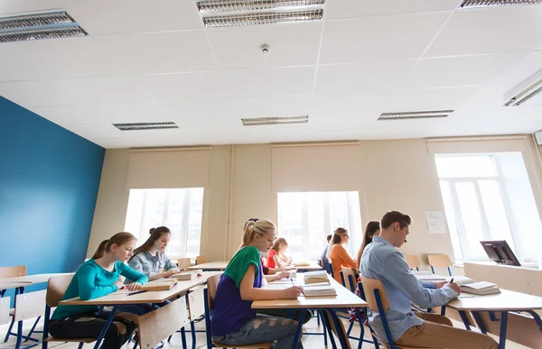 Grupp elever med böcker skriver skolan test — Stockfoto