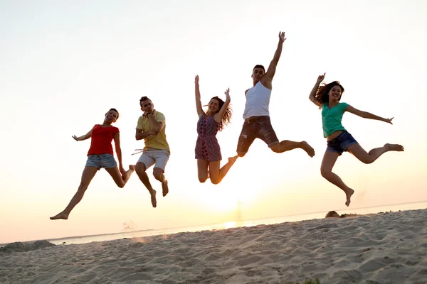 Ler vänner dansa och hoppa på stranden — Stockfoto