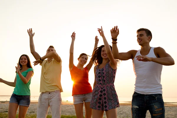 Smiling friends dancing on summer beach — Stock Photo, Image