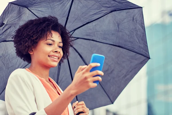 Business woman with umbrella texting on smartphone — стоковое фото