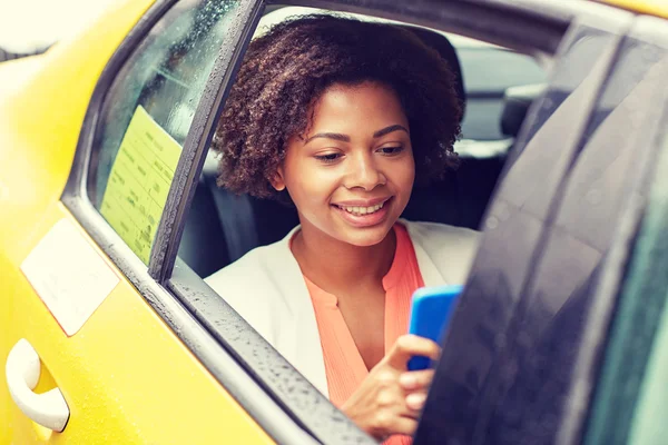 Glückliche Afrikanerin tickt im Taxi auf Smartphone — Stockfoto