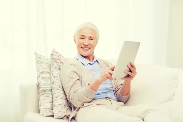 Счастливая пожилая женщина с планшетным компьютером дома — стоковое фото