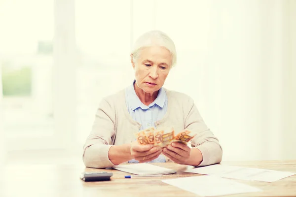 Seniorin mit Geld und Papieren zu Hause — Stockfoto