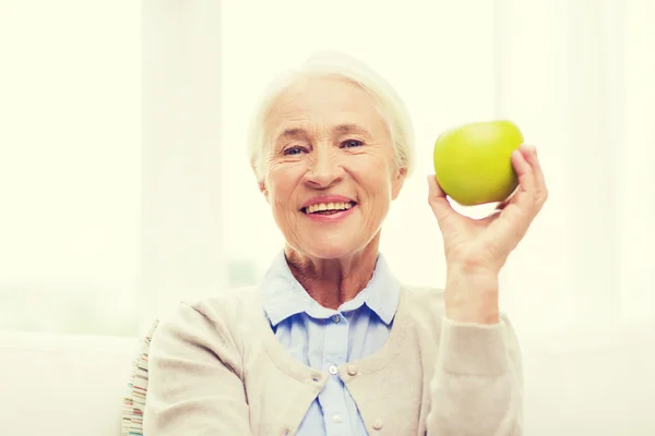 Mulher sênior feliz com maçã verde em casa — Fotografia de Stock