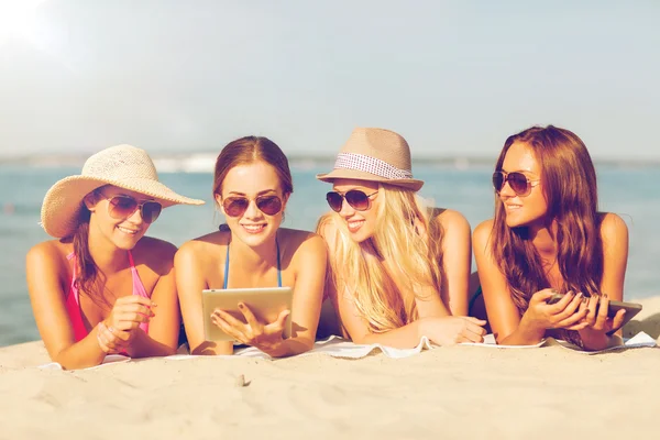 Grupo de mulheres jovens sorridentes com comprimidos na praia — Fotografia de Stock