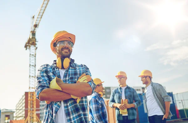 Grupo de construtores sorridentes em hardhats ao ar livre — Fotografia de Stock