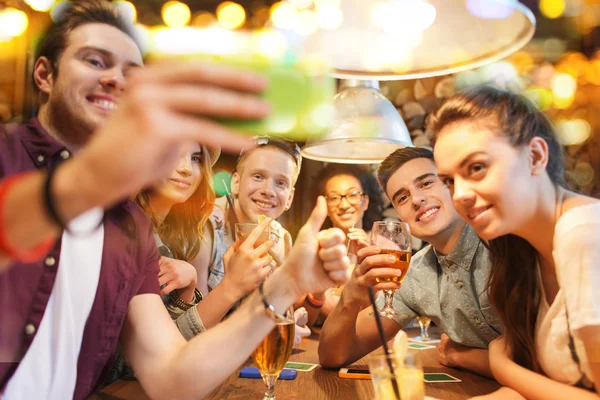 Amigos felizes com smartphone tomando selfie no bar — Fotografia de Stock