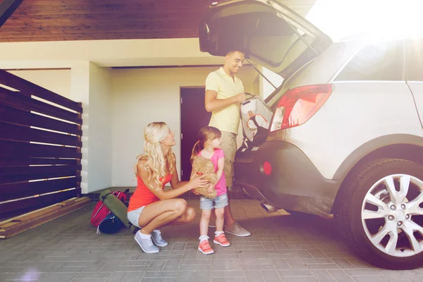 Famiglia felice imballaggio cose per auto a casa parcheggio — Foto Stock