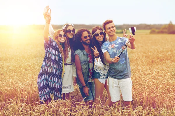 Amigos hippies con smartphone en palo selfie —  Fotos de Stock