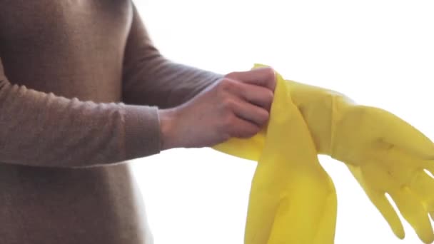 Женщина надевает резиновые перчатки для работы по дому — стоковое видео