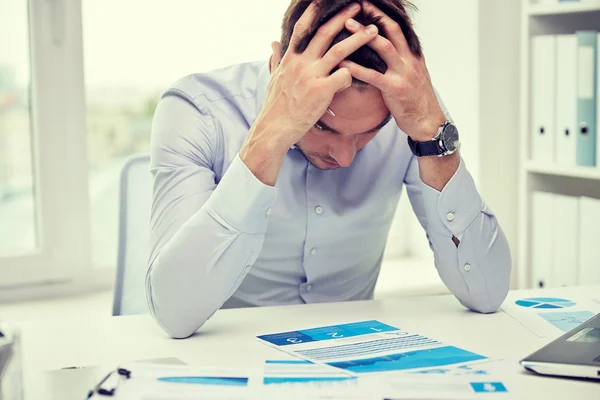 Homem de negócios estressado com papéis no escritório — Fotografia de Stock