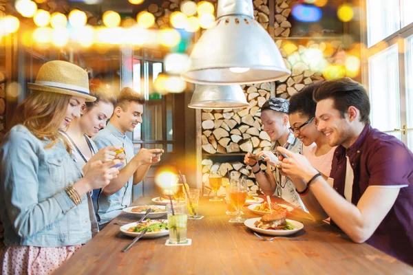 Happy friends with smartphones picturing food — Stock Photo, Image