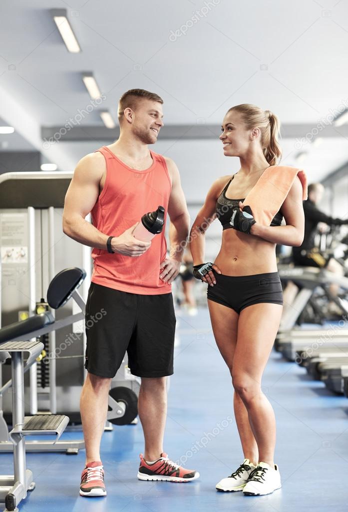 Smiling man and woman talking in gym Stock Photo by