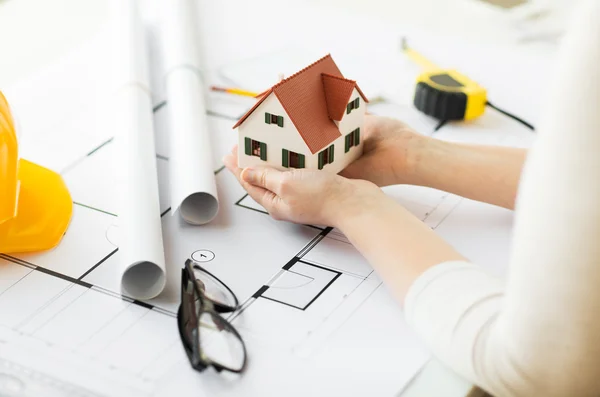 Hands with house model above blueprint — Stock Photo, Image