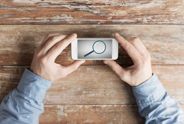 Hands with magnifier on smartphone — Stock Photo, Image