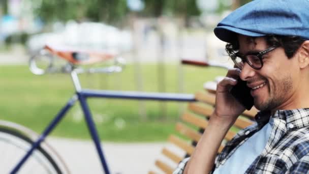 Мужчина звонит по смартфону, сидя на скамейке — стоковое видео