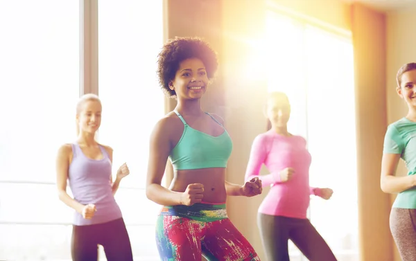 Groupe de personnes souriantes dansant dans la salle de gym — Photo