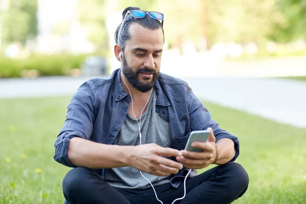Άνθρωπος με ακουστικά και το έξυπνο κινητό τηλέφωνο — Φωτογραφία Αρχείου