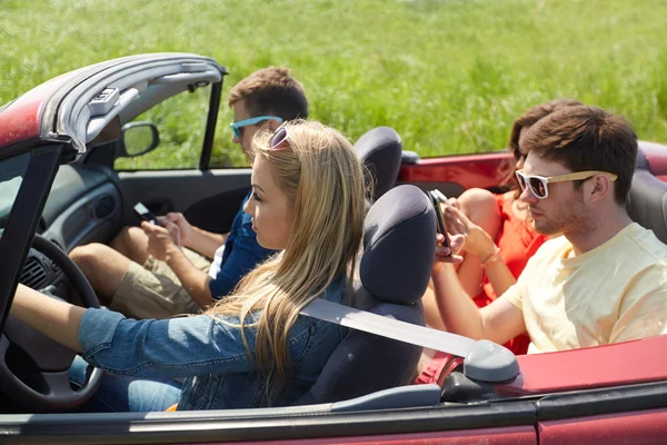 Amigos com smartphones dirigindo em carro cabriolet — Fotografia de Stock