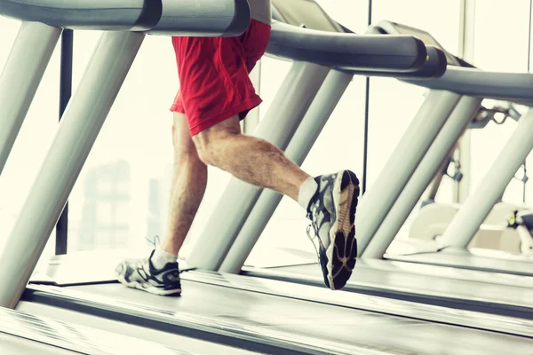Mužské nohy běží na běžeckém pásu v tělocvičně — Stock fotografie