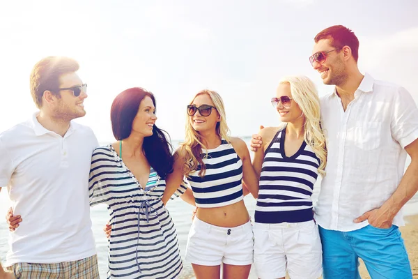 Amici sorridenti in occhiali da sole che parlano sulla spiaggia — Foto Stock