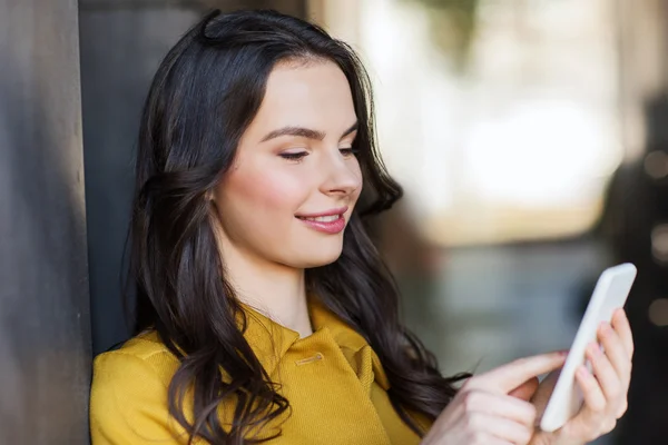 Sonriente joven mujer mensajes de texto en el teléfono inteligente —  Fotos de Stock