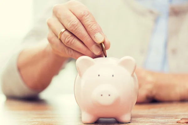 Senior vrouw hand geld om piggy bank — Stockfoto