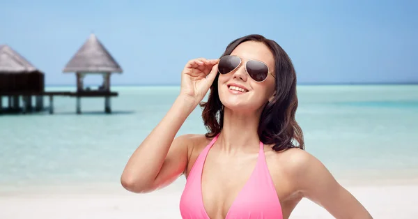 Счастливая женщина в солнечных очках и бикини на пляже — стоковое фото