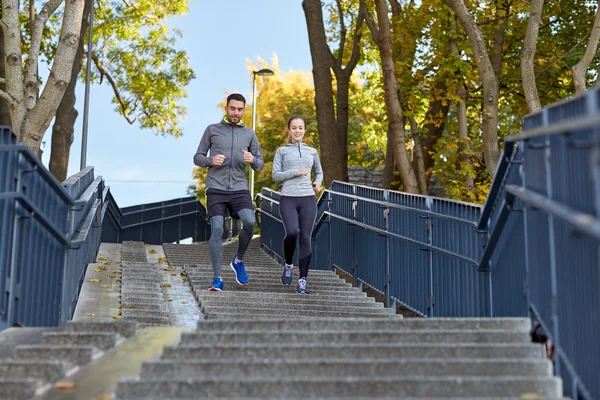 Happy couple running downstairs in city — Stock Photo, Image