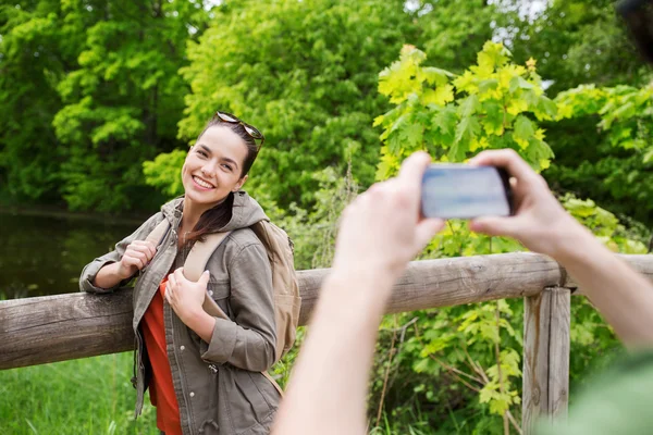 Couple with backpacks taking picture by smartphone — Stock Photo, Image