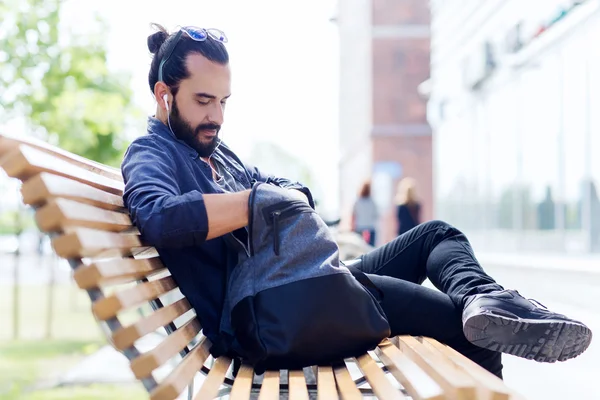 Homem com mochila e fones de ouvido na cidade — Fotografia de Stock