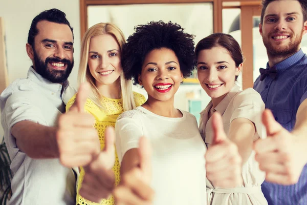 Happy creative team showing thumbs up in office — Stock Photo, Image