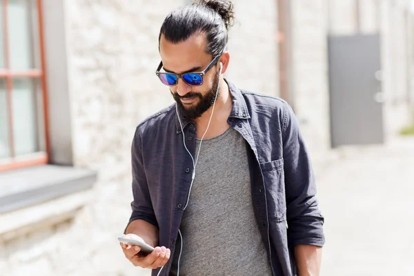 Hombre con auriculares y smartphone caminando en la ciudad — Foto de Stock