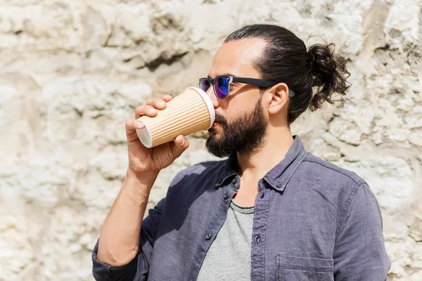Человек пьет кофе из бумажной чашки на улице — стоковое фото