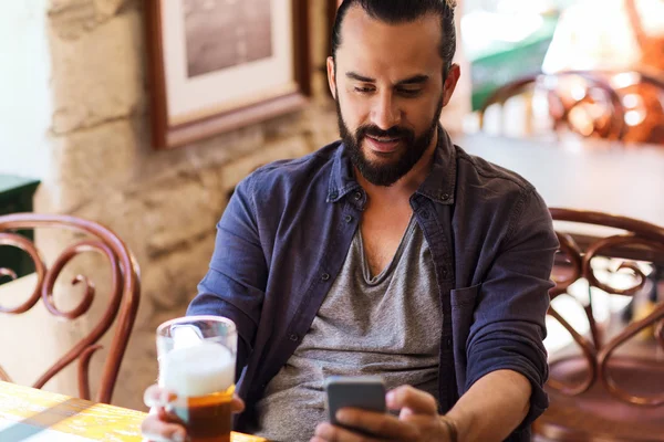 Man with smartphone drinking beer at bar or pub — Stock Photo, Image