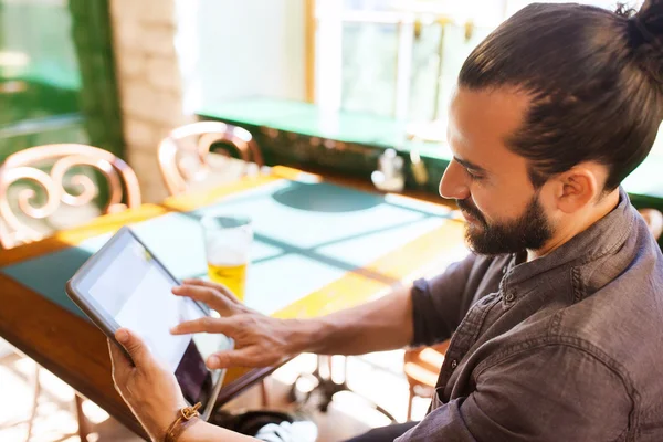 Man met tablet pc drinken bier bij bar of pub — Stockfoto