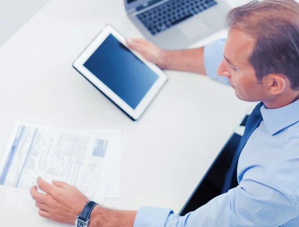 Geschäftsmann mit Tablet-PC und Papieren im Büro — Stockfoto