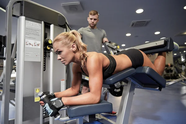 Hombres y mujeres flexionando los músculos en la máquina de gimnasio —  Fotos de Stock