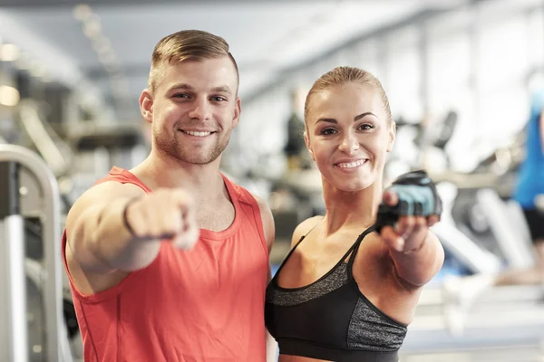 Happy man and woman pointing finger to you in gym — Stock Photo, Image