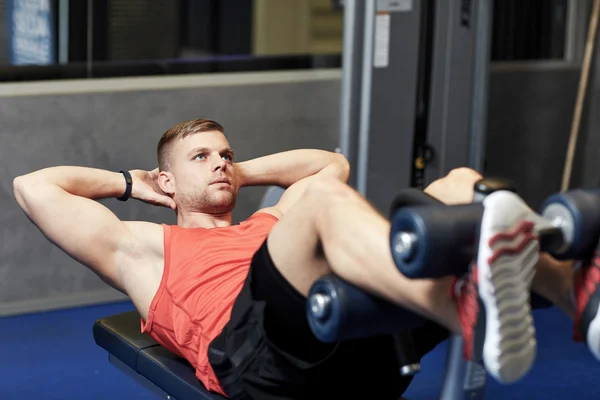Hombre joven haciendo ejercicios abdominales en el gimnasio — Foto de Stock